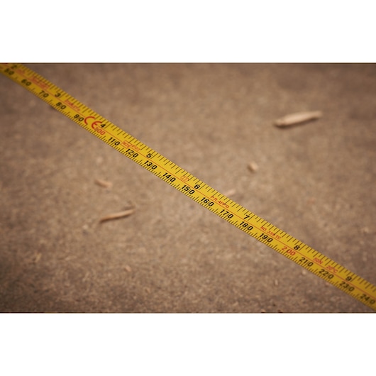 STANLEY 0-34-107 yellow measuring tape with black and red markings, extended across a brown surface.