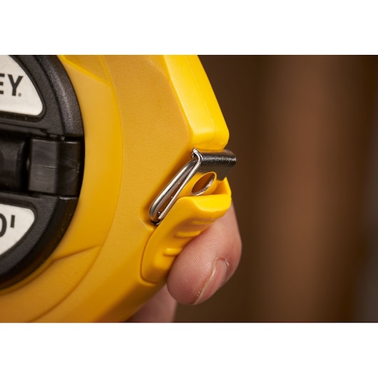 STANLEY 0-34-107 yellow tape measure close-up showing metal hook and hand detail.