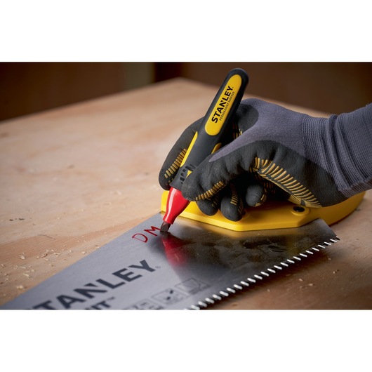 STANLEY 0-47-315 marker held by gloved hand writing on a saw blade on a wooden workbench.