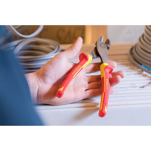 Stanley 0-84-004 insulated pliers with red-yellow handles, held in hand, close-up photo.