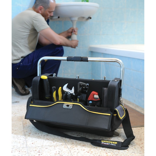STANLEY 1-70-719 tool bag with tools, open with handle, on bathroom floor during plumbing work.