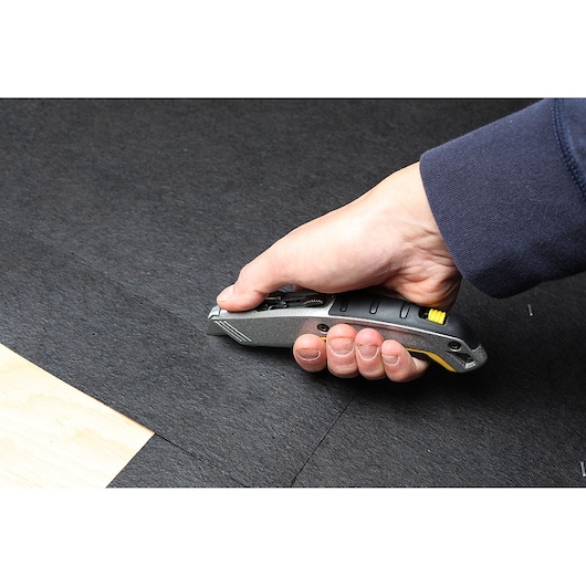 Photo of STANLEY 10-789 utility knife cutting black material, handheld close-up.