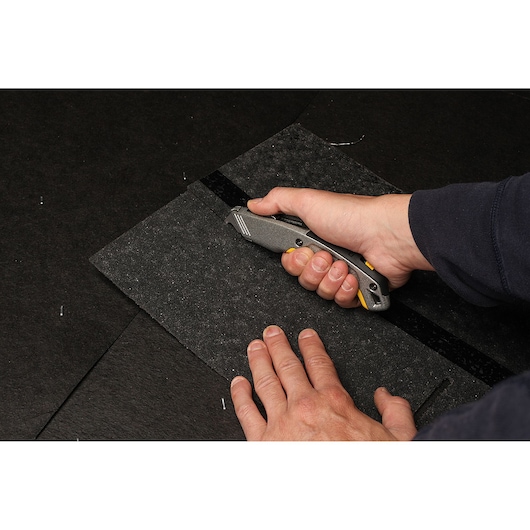 Photo of a person cutting roofing felt with a STANLEY 10-789 utility knife, product in use.