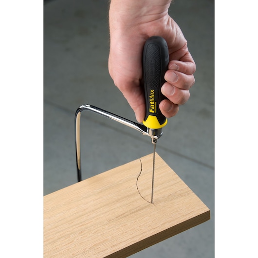 Photo of STANLEY 15-104 coping saw with black and yellow handle cutting curved line in wood.