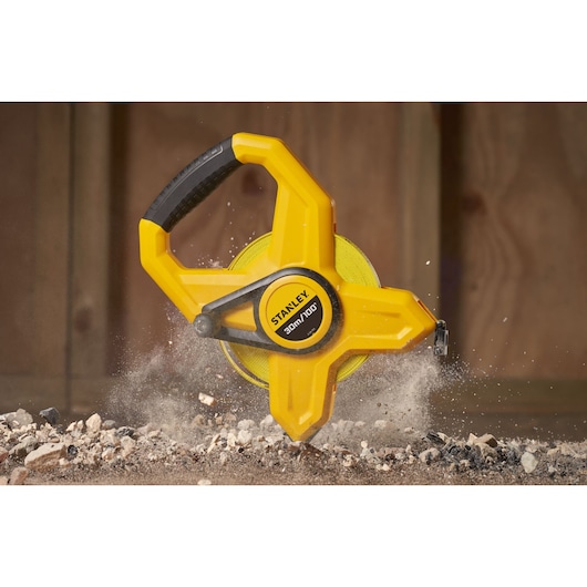 Photo of STANLEY 34-791 open reel yellow tape measure on construction debris, close-up side view.