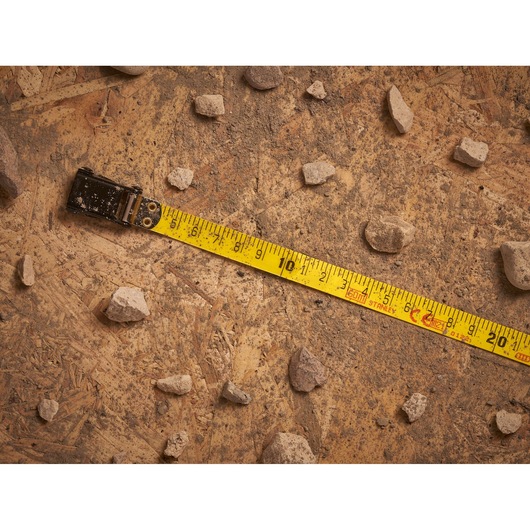 STANLEY 2-34-795 tape measure extended on dusty wood with scattered rocks, top view photography.