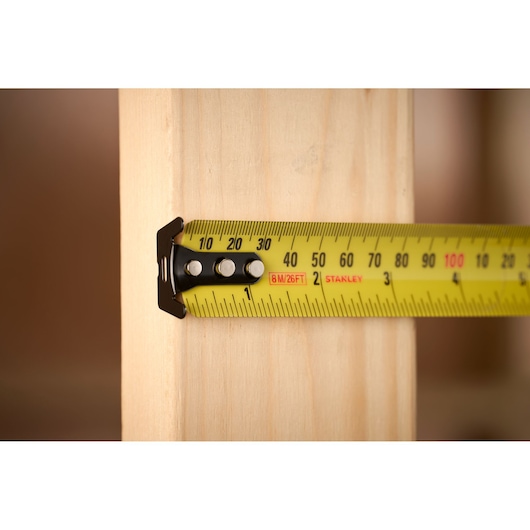 STANLEY 33-731 tape measure photography showing yellow tape measuring wooden plank close-up.