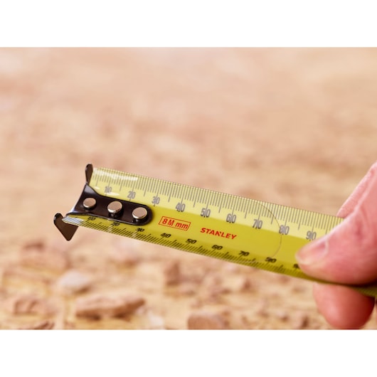 Photo of STANLEY 33-732 tape measure extended, yellow blade with black markings and hook tip.