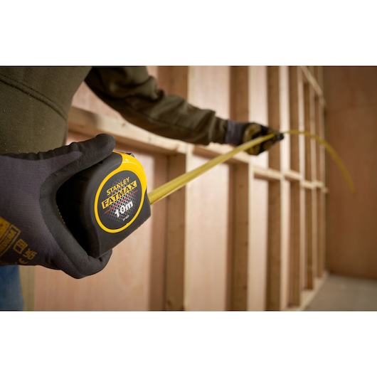 STANLEY 33-829 tape measure in use, yellow and black casing, construction setting.
