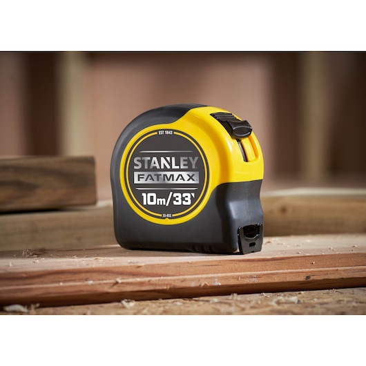 STANLEY 33-832 FatMax tape measure, black and yellow, photography, shown on wooden planks.
