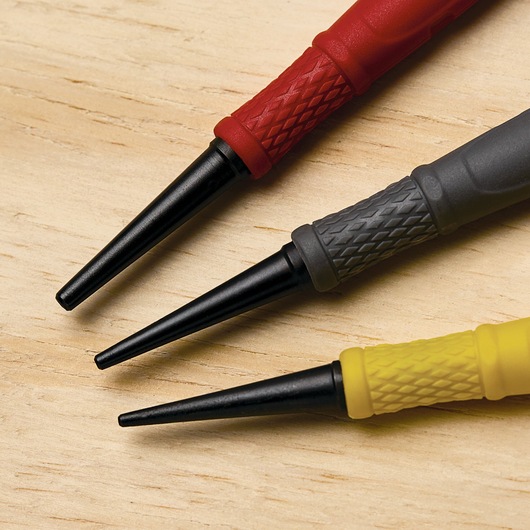 STANLEY 58-930 steel punch set with red, gray, yellow textured grips, close-up on wood surface.