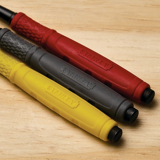 STANLEY 58-930 assorted color punch tools, yellow, black, and red, close-up on wooden surface.