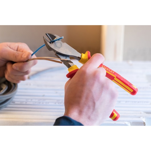 STANLEY 84-004-S insulated wire cutter with red and yellow handle, close-up in use cutting cables.