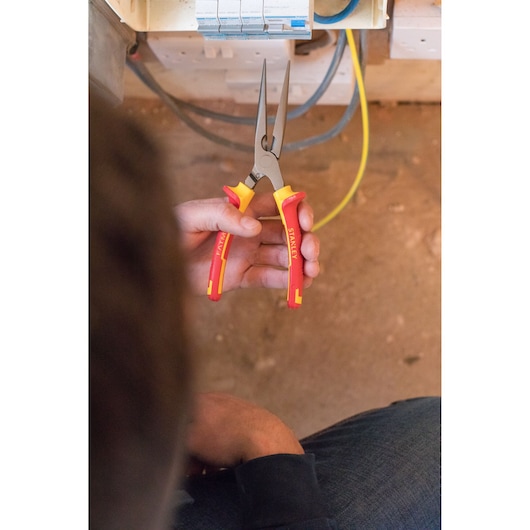 Photo of STANLEY 84-007-S insulated long nose pliers with red and yellow handles being used for electrical work.