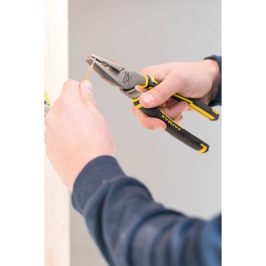 STANLEY 89-868 pliers with black and yellow grip, in use cutting copper wire, close-up.