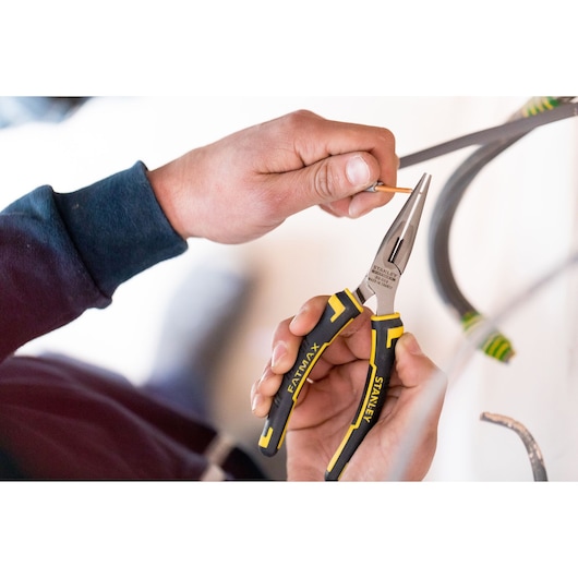 STANLEY 89-869 long nose pliers with black and yellow handles used to grip a wire during electrical work.