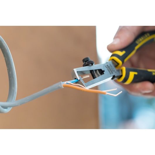 STANLEY 89-873 wire stripper pliers in use stripping insulation from electric wires, close-up photography.