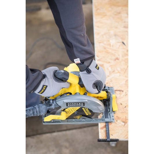STANLEY FME301 circular saw cutting plywood, worker hands in gloves holding tool, top view.
