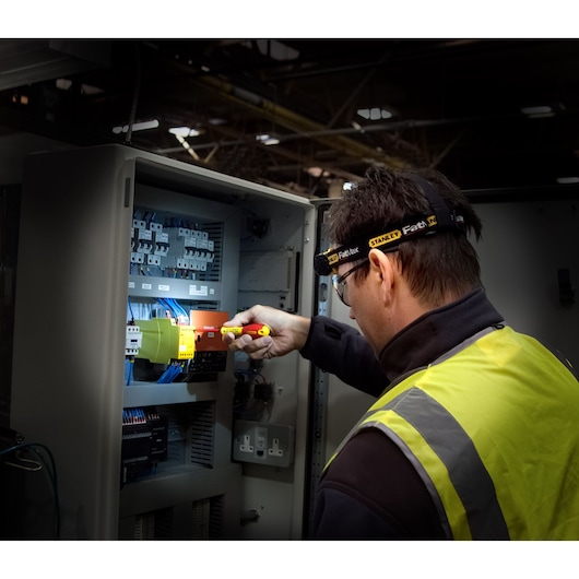 STANLEY FMHT0-70767 electrical tester being used on control panel, worker in high-visibility vest.