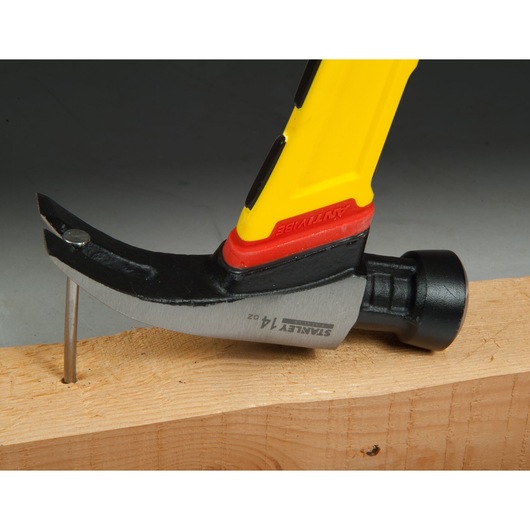 STANLEY FMHT1-51260 claw hammer with yellow handle, side view, pulling nail from wood plank.