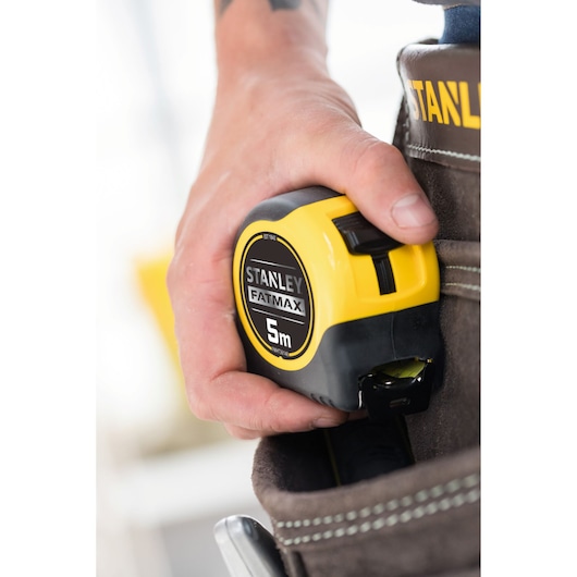 Photo of STANLEY FATMAX 5m tape measure, SKU FMHT36148-3, held in a tool belt pocket.