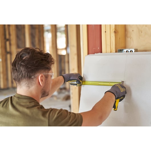 Photo of STANLEY FMHT38219-3 tape measure used to measure drywall in a construction setting.