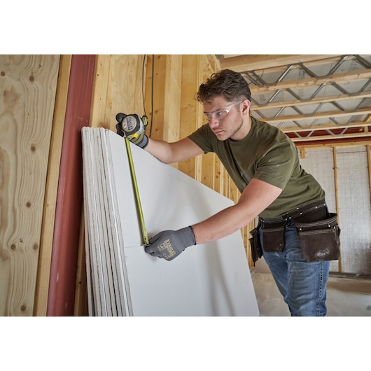 STANLEY FMHT38219-3 tape measure used for measuring drywall, indoor construction setting.