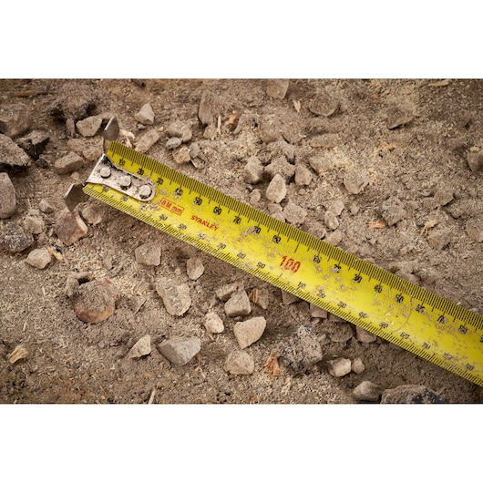 STANLEY FMHT38219-3 yellow tape measure on rocky ground, close-up photography.