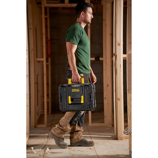 STANLEY FMST1-75502 black and yellow toolbox carried by person at construction site.