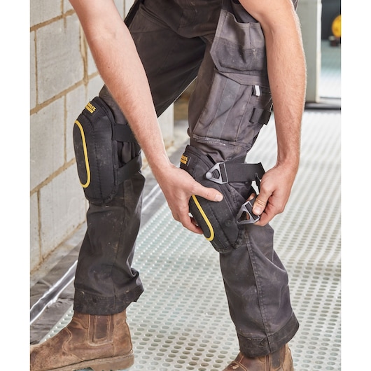 STANLEY FMST82962-1 knee pads with yellow trim worn by worker on site, close-up photography.