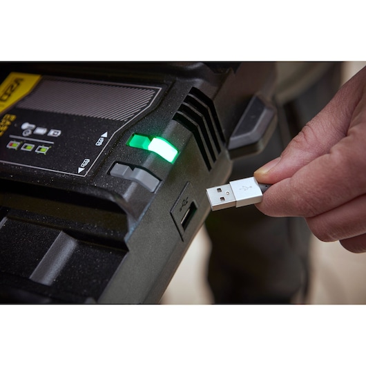 STANLEY SFMCB24 battery charger with green indicator and person plugging in USB cable, close-up.