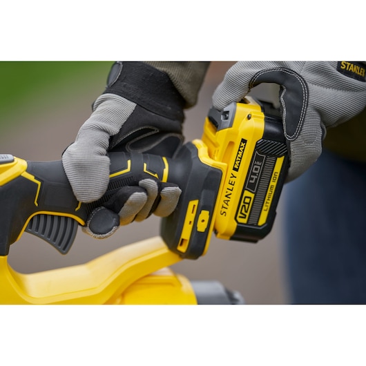 Photo of STANLEY SFMCBL7B cordless tool in use, focus on handle and battery, yellow and black design.