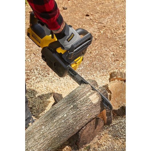 STANLEY SFMCCS630B cordless chainsaw cutting a log, shown in use outdoors.
