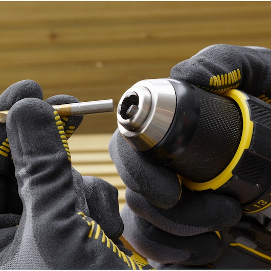 STANLEY SFMCD720DR2 drill being fitted with a bit, close-up view, gloves handling tool.