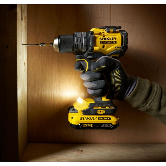 Photo of STANLEY SFMCD725B cordless drill driver in use, yellow and black design, being used to drill into wood.