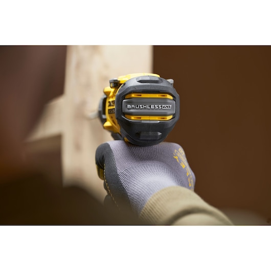 Photo of STANLEY SFMCD726D2K cordless brushless drill held by a gloved hand in a workshop setting.