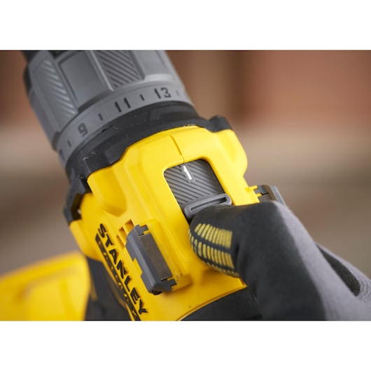 Photo of STANLEY SFMCD726D2K drill close-up showing speed selector and gloved hand adjusting switch.