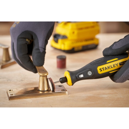 STANLEY SFMCE030B rotary tool polishing brass hardware on a wooden surface, close-up photography.