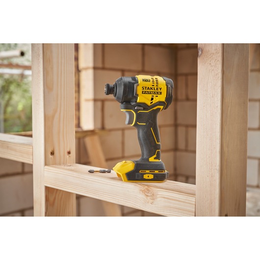 STANLEY SFMCF811B-XJ impact driver in yellow and black on wooden frame at construction site.