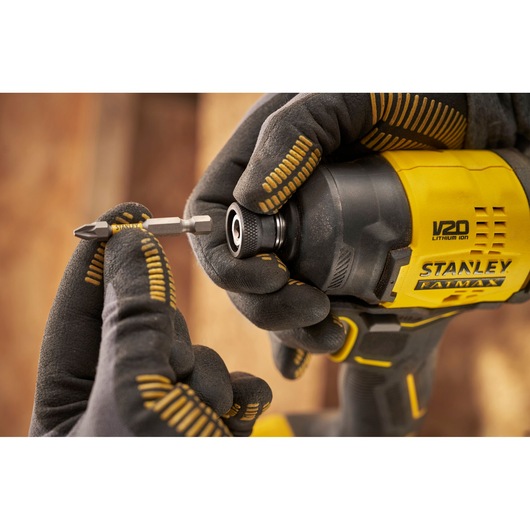 Photo of STANLEY SFMCF811B-XJ impact driver being fitted with a bit, close-up view with gloved hands.