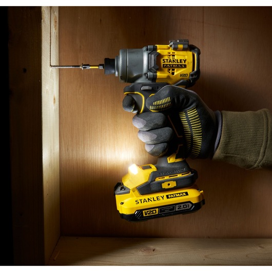 Photo of STANLEY SFMCF830D2K V20 FATMAX impact driver in use drilling screw into wooden board.