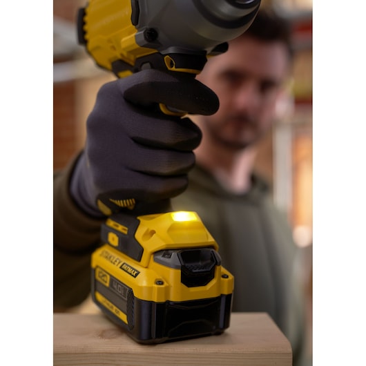 STANLEY SFMCF940B cordless impact wrench in yellow and black, shown in use on wood.