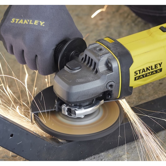 Photo of STANLEY SFMCG400M1S angle grinder cutting metal with sparks, close-up, yellow and black tool in use.