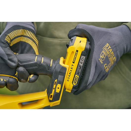 STANLEY SFMCHT650D1 photography of V20 Fatmax tool with battery, close-up of gloved hands.