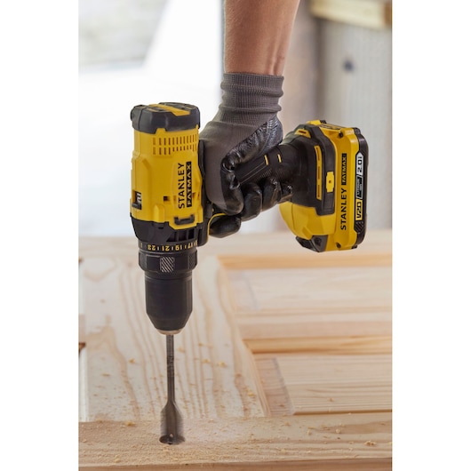 STANLEY SFMCK470D2 cordless drill in use, drilling into wood, close-up side angle.