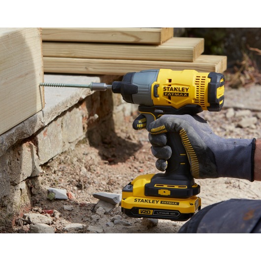 STANLEY SFMCK470D2 impact driver being used to drive a screw into wood, close-up view outdoors.