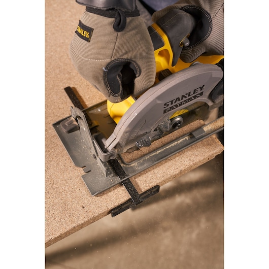 Photo of STANLEY SFMCK470D2 circular saw cutting wood, close-up view, user wearing work gloves.
