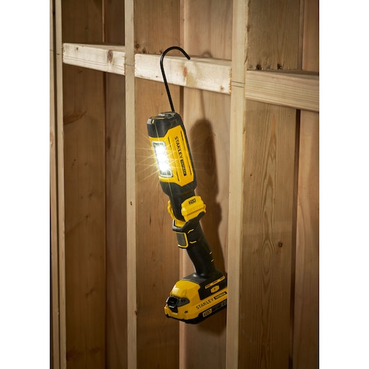 STANLEY SFMCL050B 18V STANLEY FATMAX V20 pivot light hanging on wooden frame, LED lit, black and yellow design.