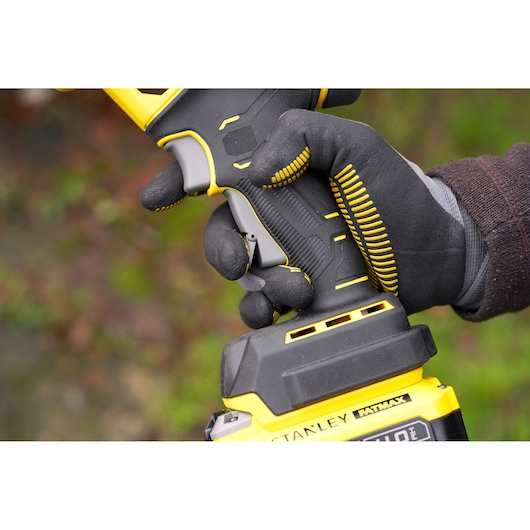 Stanley SFMCPP32B power tool handle close-up, black and yellow design, gloved hand holding grip.