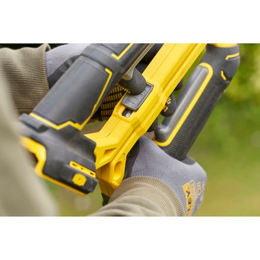 STANLEY SFMCPS515B cordless pruning saw close-up held by gloved hand outdoors.